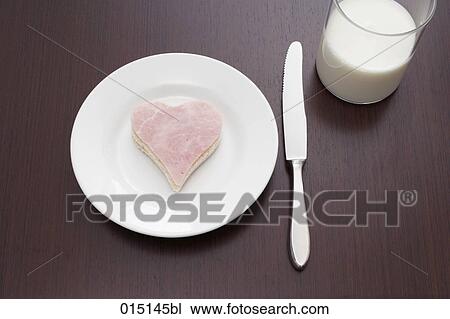Stock Image - still life of ham sandwich cut out in shape of heart on plate and glass of milk. Fotosearch