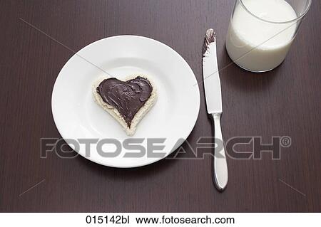 Stock Image - still life of sandwich with spread cut out in shape of heart on plate and glass of milk. Fotosearch