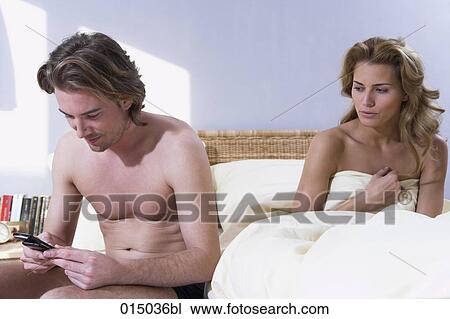 young couple in bed woman looking annoyed while man is checking his mobile phone View Large Photo Image Stock Image - young couple in bed woman looking annoyed while man is checking his mobile phone. Fotosearch