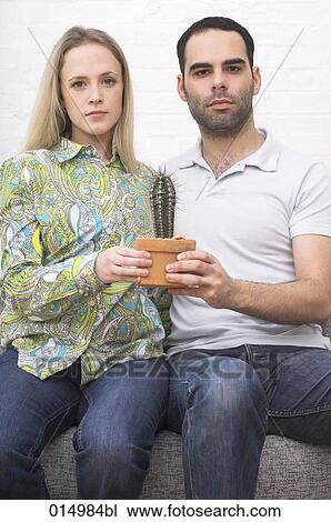young couple sitting on armchair together holding potted cactus View Large Photo Image Stock Image - young couple sitting on armchair together holding potted cactus. Fotosearch