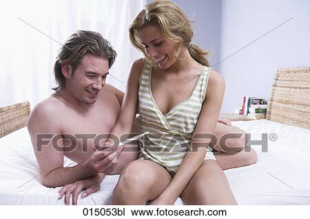 young couple sitting on bed happy about result of pregnancy test View Large Photo Image Stock Image - young couple sitting on bed happy about result of pregnancy test. Fotosearch