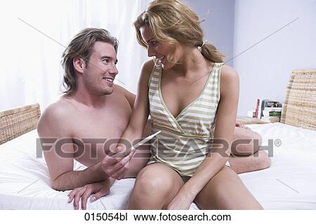 young couple sitting on bed happy about result of pregnancy test View Large Photo Image Stock Image - young couple sitting on bed happy about result of pregnancy test. Fotosearch