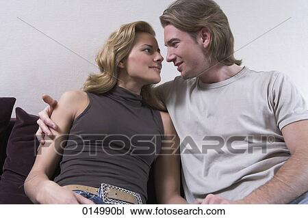 young couple sitting on sofa together tenderly looking at each other View Large Photo Image Stock Image - young couple sitting on sofa together tenderly looking at each other. Fotosearch