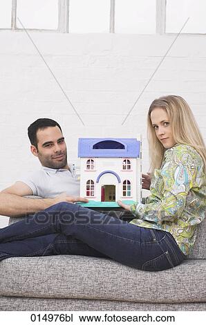 young couple sitting together on armchair holding miniature house View Large Photo Image Stock Image - young couple sitting together on armchair holding miniature house. Fotosearch