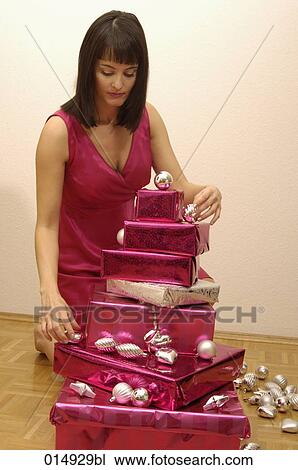 young woman decorating pile of christmas presents with baubles View Large Photo Image Stock Image - young woman decorating pile of christmas presents with baubles. Fotosearch