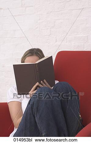 young woman sitting in armchair hiding behind book View Large Photo Image Stock Image - young woman sitting in armchair hiding behind book. Fotosearch