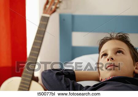 Boy lying in bed View Large Photo Image Stock Image - Boy lying in bed. Fotosearch