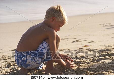 Boy playing with sand on the beach View Large Photo Image Stock Image - Boy playing with sand on the beach. Fotosearch