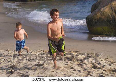 Stock Image - Boys running on beach. Fotosearch