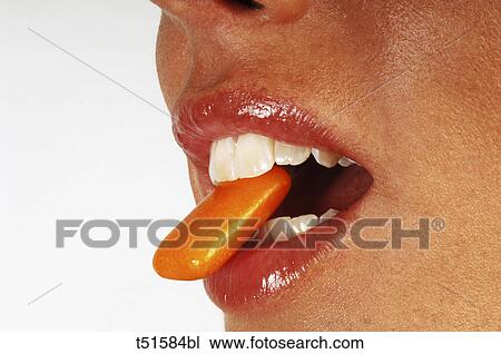 Stock Image - Close up of woman's mouth Woman eating a chewing gum. Fotosearch