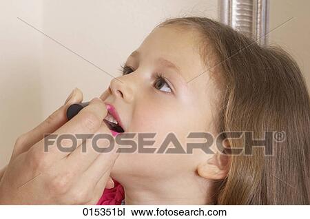 Stock Image - close-up of young girl being made up by her mother. Fotosearch