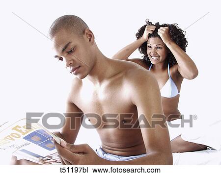 Couple on bed, desperate woman looking at him him while he's reading a magazine View Large Photo Image Stock Image - Couple on bed, desperate woman looking at him him while he's reading a magazine. Fotosearch