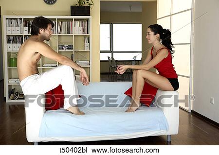 Couple sitting on sofa looking at each other View Large Photo Image Stock Image - Couple sitting on sofa looking at each other. Fotosearch
