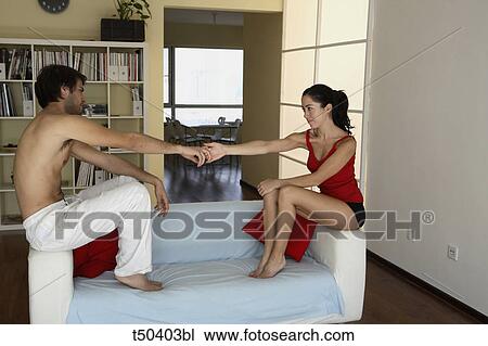 Couple sitting on sofa shaking hands View Large Photo Image Stock Image - Couple sitting on sofa shaking hands. Fotosearch