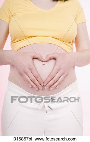 detail of pregnant young woman forming heart with hands over her belly View Large Photo Image Stock Image - detail of pregnant young woman forming heart with hands over her belly. Fotosearch