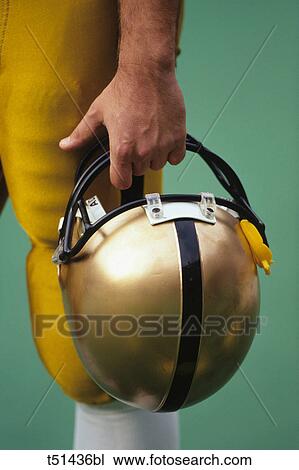 Stock Image - Football player holding his helmet. Fotosearch
