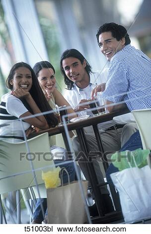 Stock Image - Group of friends sitting on a table outdoors. Fotosearch