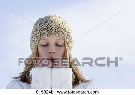 Stock Image - headshot of teenage girl in winter warming her hands. Fotosearch