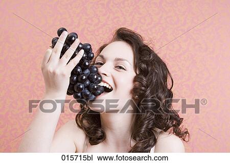 headshot of young woman biting into black grapes View Large Photo Image Stock Image - headshot of young woman biting into black grapes. Fotosearch