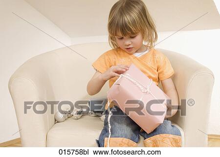 little girl sitting on chair unwrapping christmas present View Large Photo Image Stock Image - little girl sitting on chair unwrapping christmas present. Fotosearch
