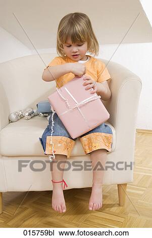 little girl sitting on chair unwrapping christmas present View Large Photo Image Stock Image - little girl sitting on chair unwrapping christmas present. Fotosearch