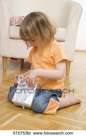 Stock Image - little girl unwrapping present. Fotosearch