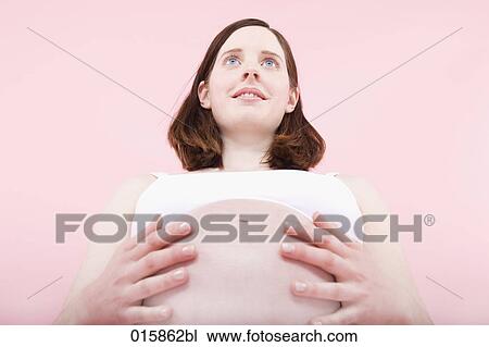 low angle portrait of pregnant young woman holding her belly View Large Photo Image Stock Image - low angle portrait of pregnant young woman holding her belly. Fotosearch