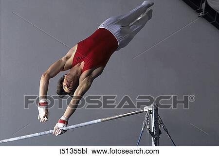 Stock Image - Male gymnast performing on the high bar. Fotosearch