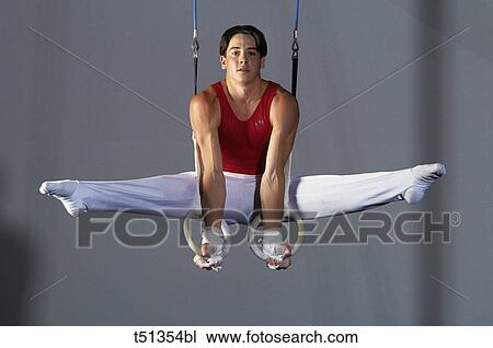 Stock Image - Male gymnast performing on the rings. Fotosearch