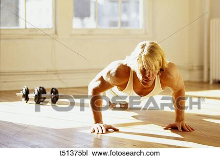 Stock Image - Man performing pushups in gym. Fotosearch
