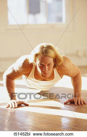 Stock Image - Man performing pushups in gym. Fotosearch