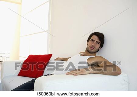 Man sitting on sofa View Large Photo Image Stock Image - Man sitting on sofa. Fotosearch