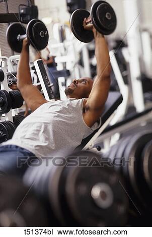 Man working out with hand weights in gym View Large Photo Image Stock Image - Man working out with hand weights in gym. Fotosearch