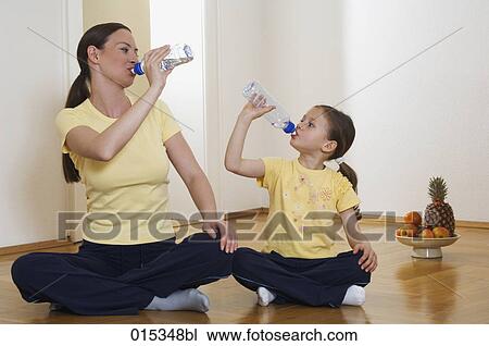mother and daughter sitting on floor together drinking water from plastic bottles View Large Photo Image Stock Image - mother and daughter sitting on floor together drinking water from plastic bottles. Fotosearch