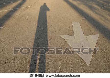 Person's shadow and street arrow sign View Large Photo Image Stock Image - Person's shadow and street arrow sign. Fotosearch