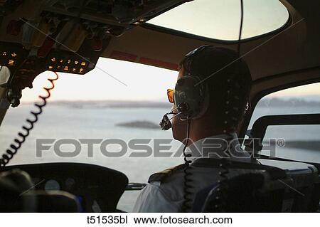 Stock Image - Pilot in helicopter cockpit. Fotosearch