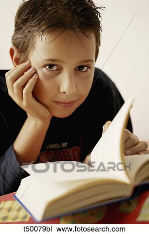 Stock Image - Portrait of boy reading book. Fotosearch