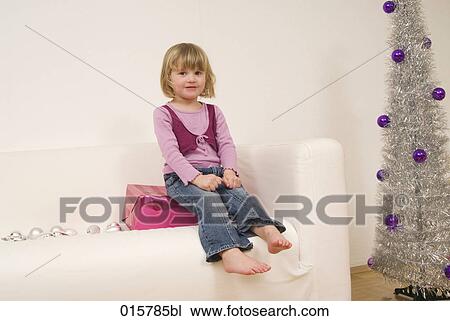 portrait of little girl sitting on sofa near christmas tree View Large Photo Image Stock Image - portrait of little girl sitting on sofa near christmas tree. Fotosearch