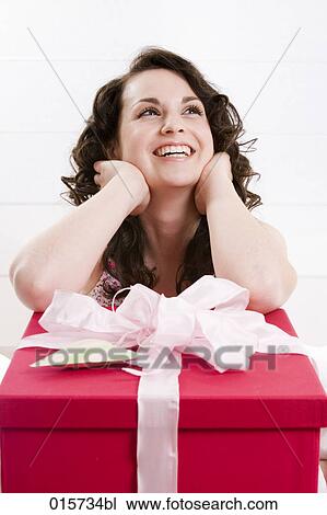 portrait of smiling young woman thinking about big present in front of her View Large Photo Image Stock Image - portrait of smiling young woman thinking about big present in front of her. Fotosearch