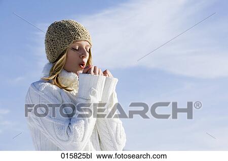 Stock Image - portrait of teenage girl in winter warming her hands. Fotosearch