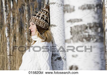 Stock Image - portrait of teenage girl leaning against tree in winter forest. Fotosearch