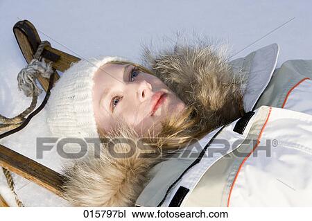 Stock Image - portrait of teenage girl relaxing on sledge. Fotosearch