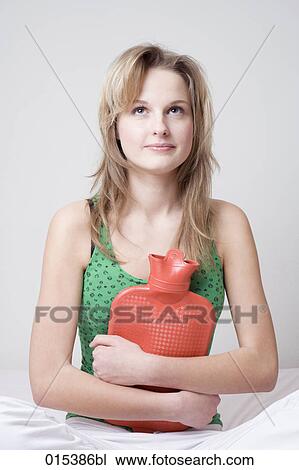 portrait of young woman in bed holding hot water bottle View Large Photo Image Stock Image - portrait of young woman in bed holding hot water bottle. Fotosearch