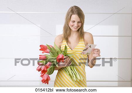 portrait of young woman in yellow summer dress holding bunch of tulips and reading love letter View Large Photo Image Stock Image - portrait of young woman in yellow summer dress holding bunch of tulips and reading love letter. Fotosearch