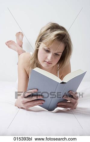 portrait of young woman lying on bed reading book View Large Photo Image Stock Image - portrait of young woman lying on bed reading book. Fotosearch