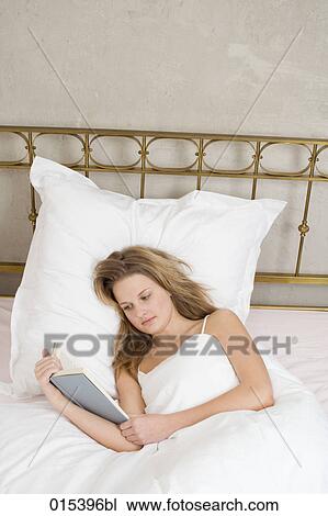 portrait of young woman reading book in bed View Large Photo Image Stock Image - portrait of young woman reading book in bed. Fotosearch