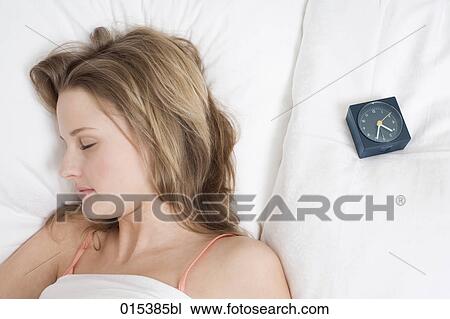 portrait of young woman sleeping in bed with alarm clock on pillow View Large Photo Image Stock Image - portrait of young woman sleeping in bed with alarm clock on pillow. Fotosearch