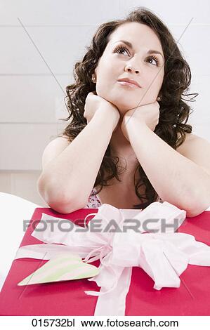 portrait of young woman thinking about big present in front of her View Large Photo Image Stock Image - portrait of young woman thinking about big present in front of her. Fotosearch