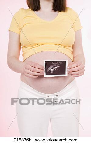 pregnant young woman holding ultrasound photograph of fetus View Large Photo Image Stock Image - pregnant young woman holding ultrasound photograph of fetus. Fotosearch