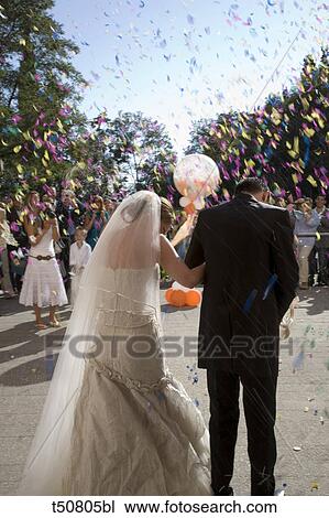Rear view of bride and groom leaving church and guest throwing flower petals View Large Photo Image Stock Image - Rear view of bride and groom leaving church and guest throwing flower petals. Fotosearch